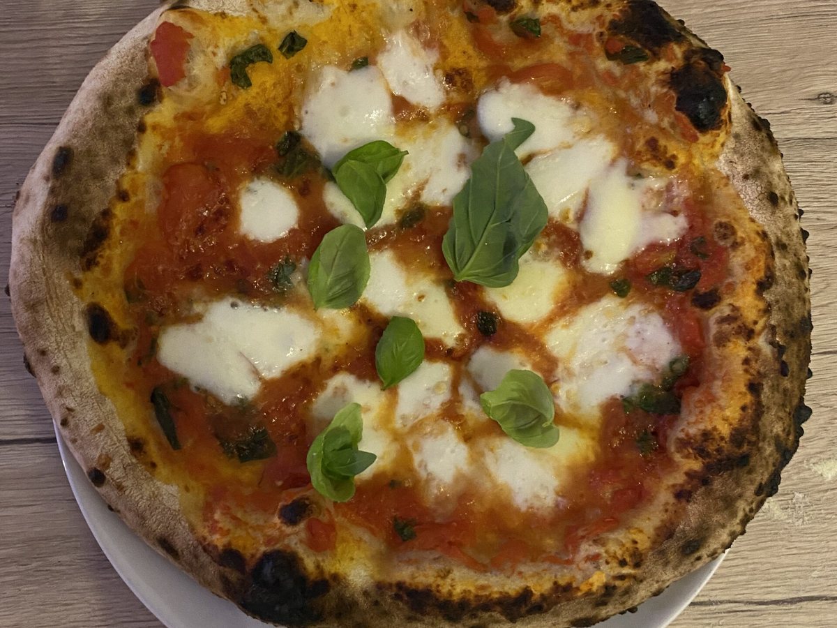 Frisch gebackene Margherita auf einem Teller am Tisch